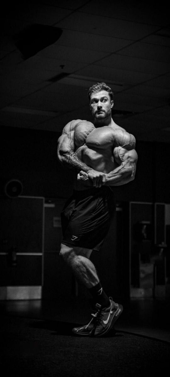 a man in the middle of a bodybuilding competition posing for a black and white photo