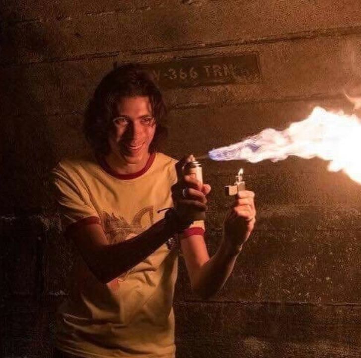 a man holding a lighter in front of a fire