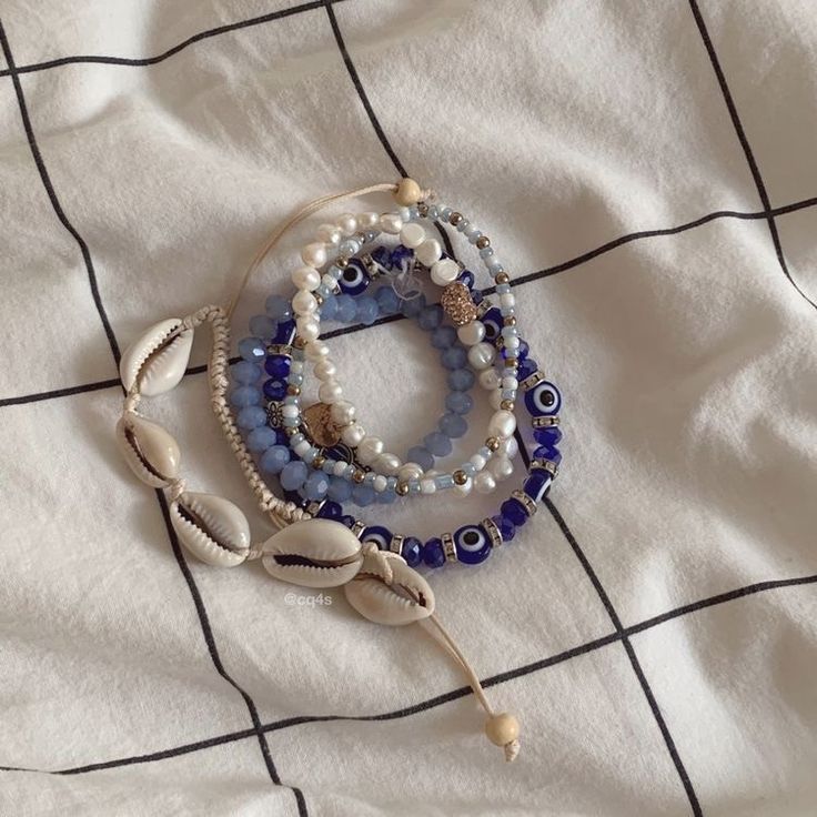 three bracelets with shells and beads on a bed