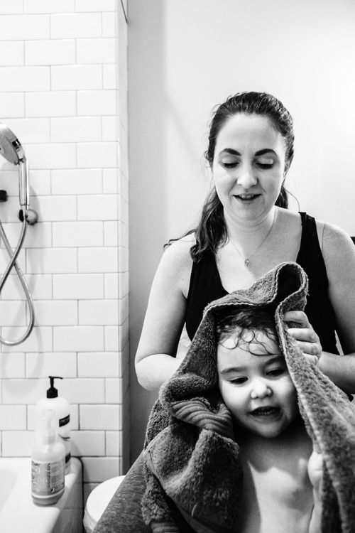 a woman is drying her child's hair in the bathroom