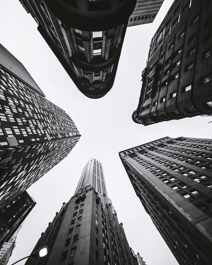 looking up at tall buildings in the city from ground level, black and white photograph