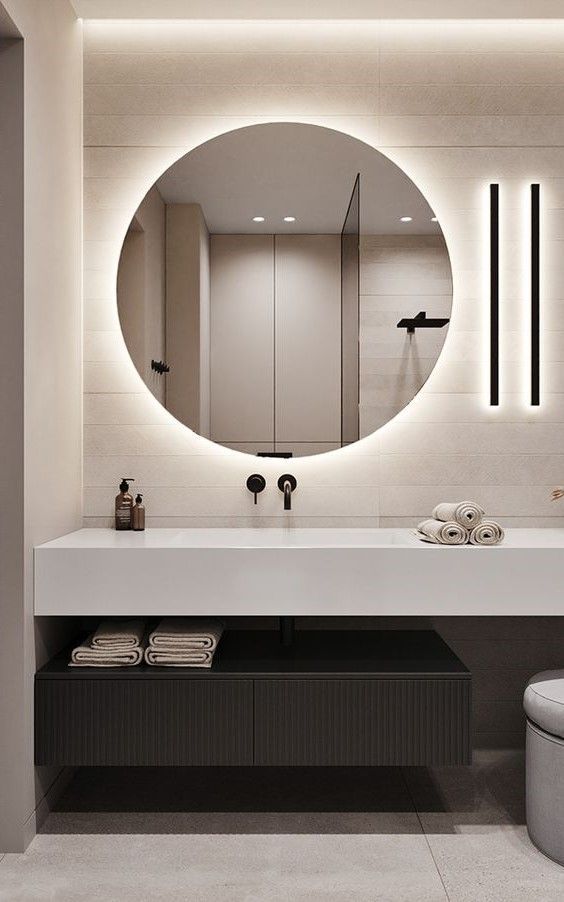 a bathroom with a large round mirror above the sink and lights on the wall behind it