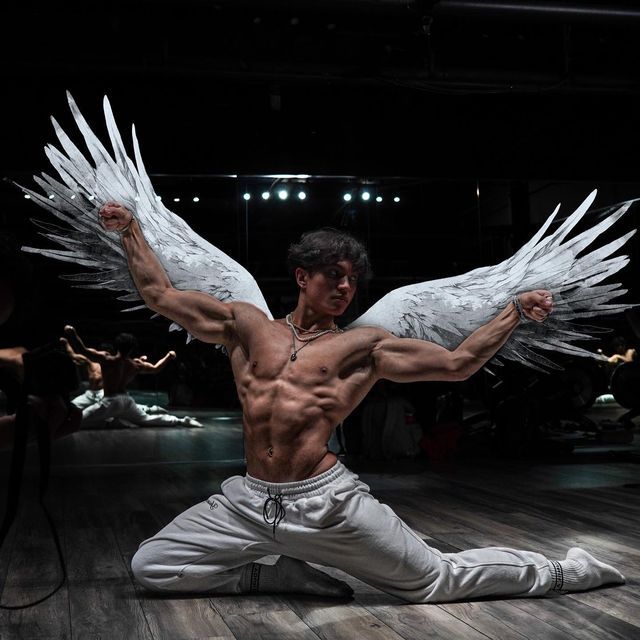 a man with angel wings on his back in the middle of a dance pose for a photo