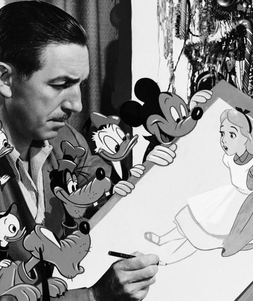 a man holding a drawing in front of mickey mouse faces and other cartoon characters behind him