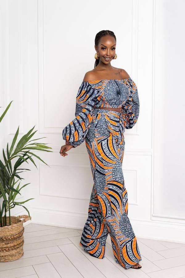 a woman standing in front of a white wall wearing a blue and orange patterned dress