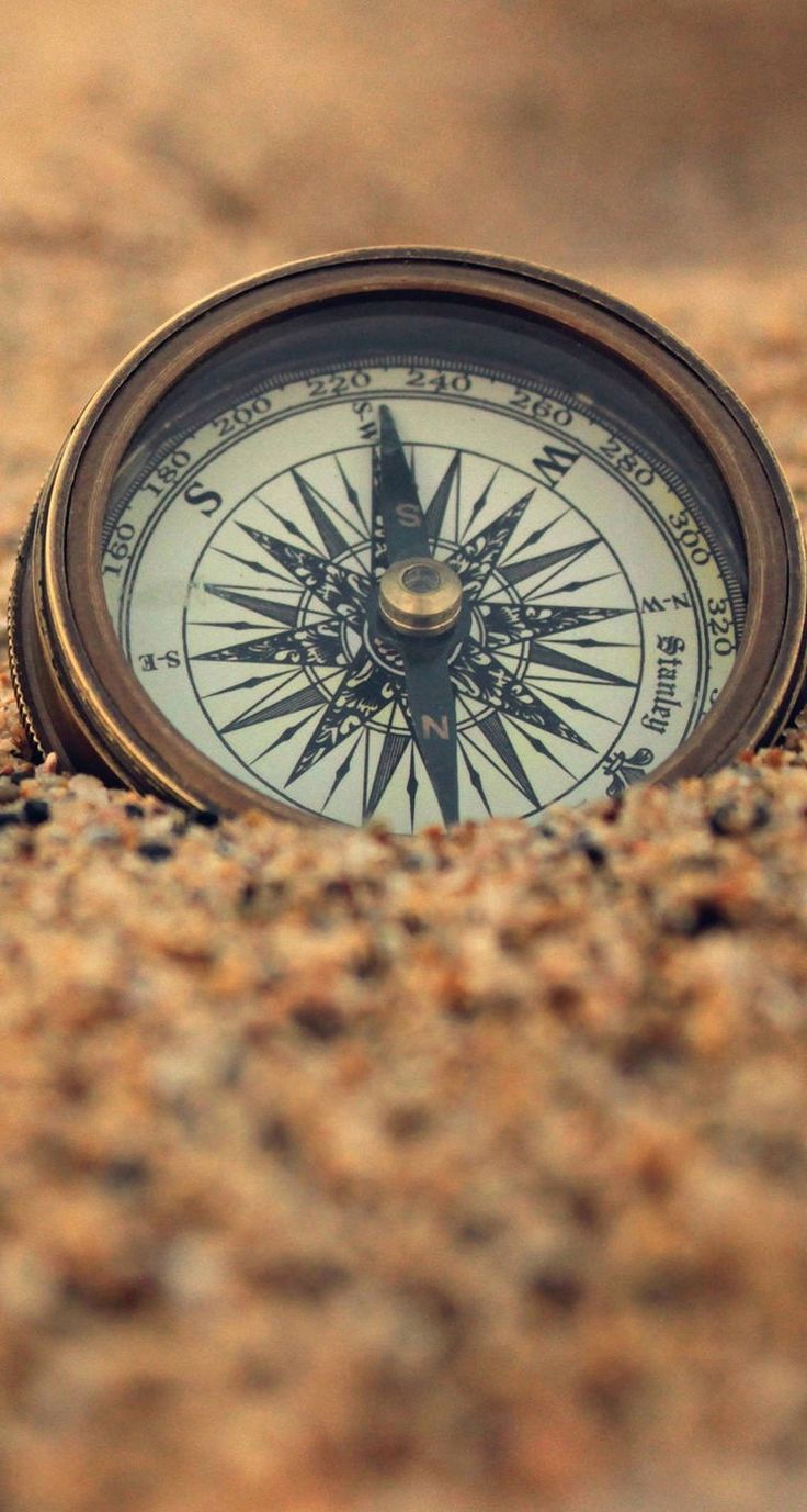 a compass sitting in the middle of some sand