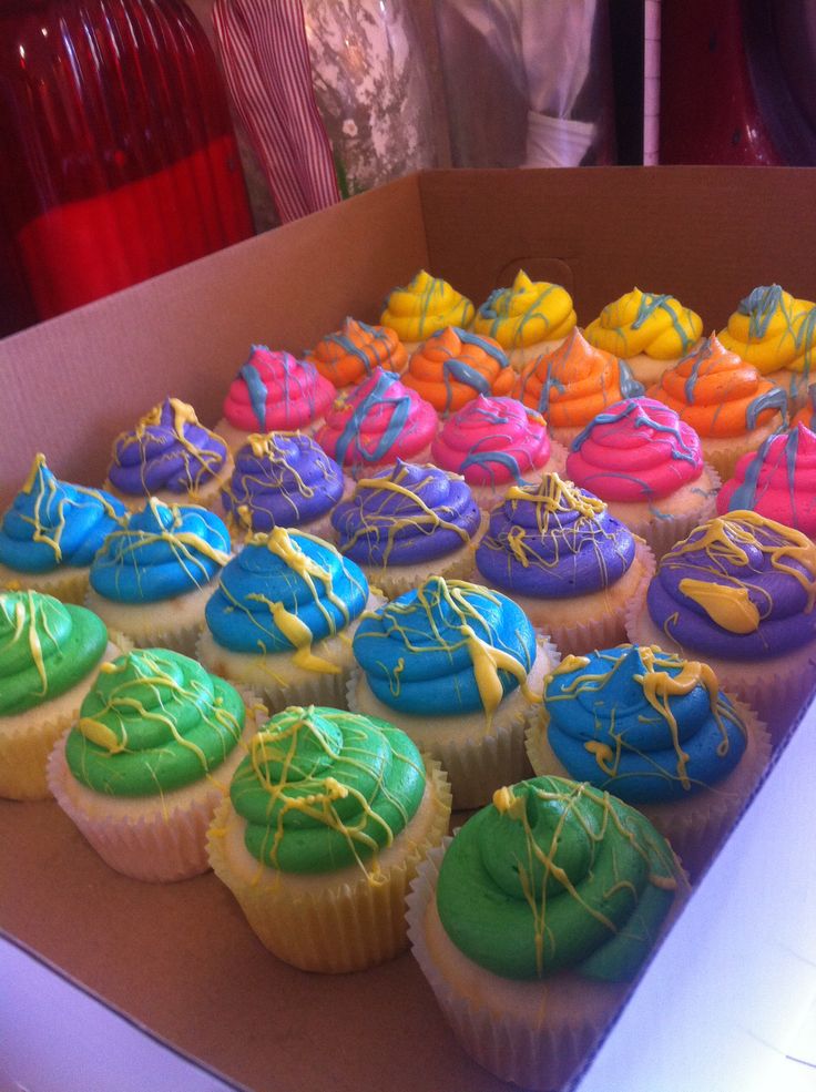 a box filled with colorful cupcakes sitting on top of a table