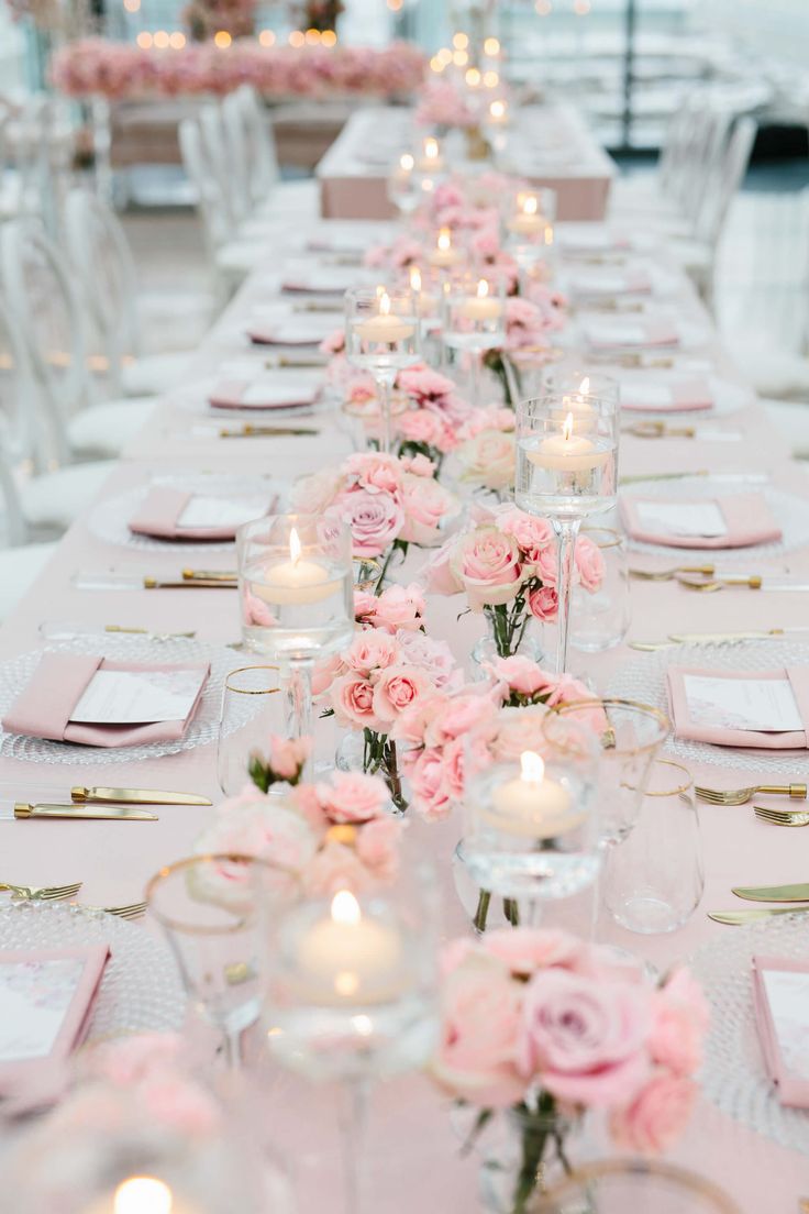 a long table is set with pink flowers and candles