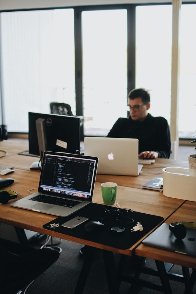 two men sitting at a table with laptops