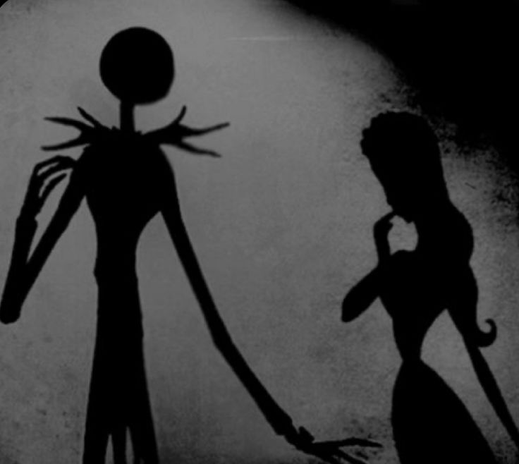 the shadow of a woman and a man holding hands in front of a dark background