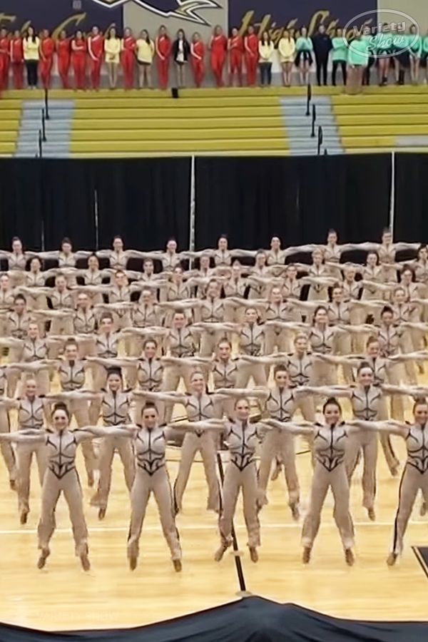 a group of people standing on top of a wooden floor in front of a crowd