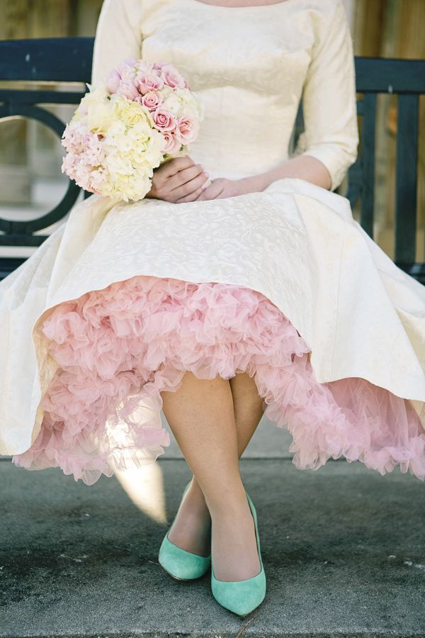 a woman sitting on a bench wearing a dress and holding a bouquet in her hand