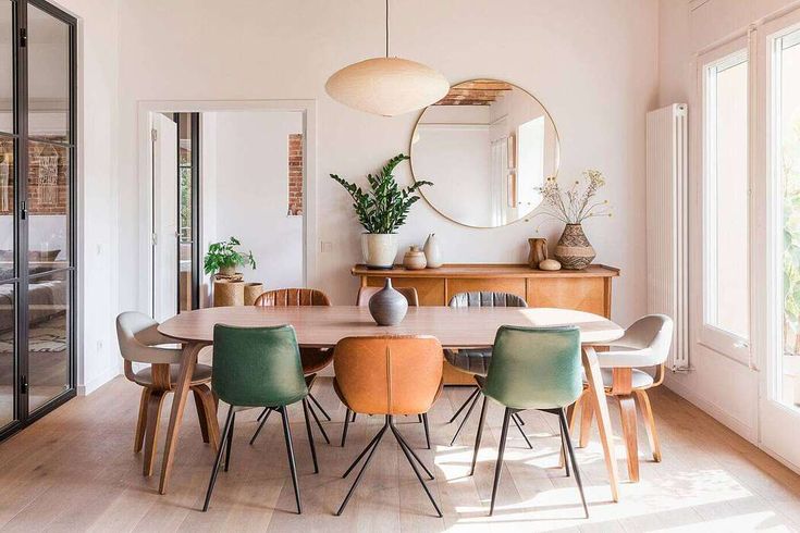 a dining room table with chairs and a round mirror