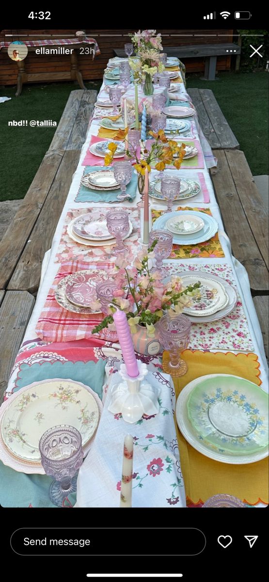 a long table with plates and flowers on it is set for an outdoor dinner party