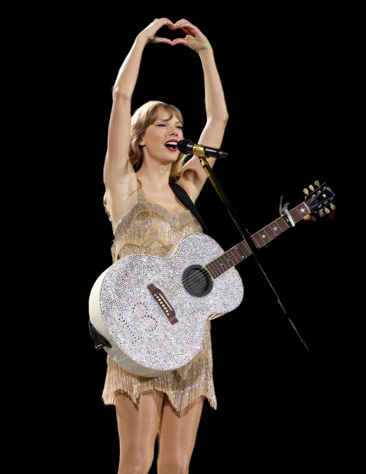 the woman is holding her guitar and making a heart shape with her hands as she sings