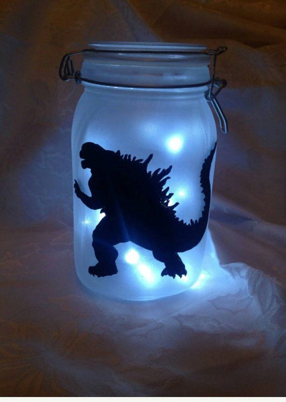 a jar with some lights in it and a godzilla silhouette on the lid that is lit up