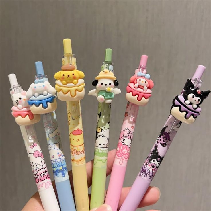 a person holding five different colored pens in their hand with hello kitty characters on them