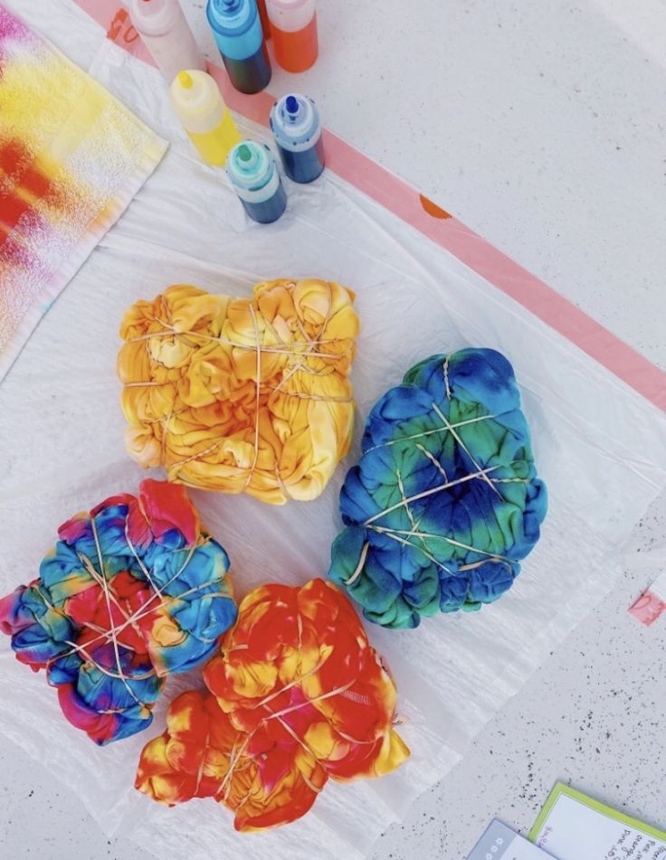 four different colored objects are sitting on the table next to some markers and paintbrushes