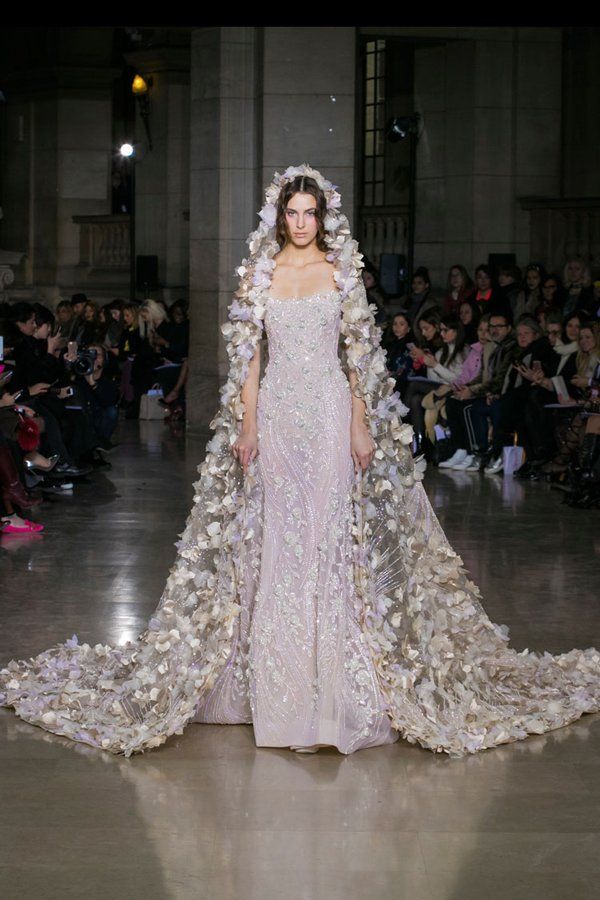 a woman in a white gown with flowers on her head and cape over her shoulders