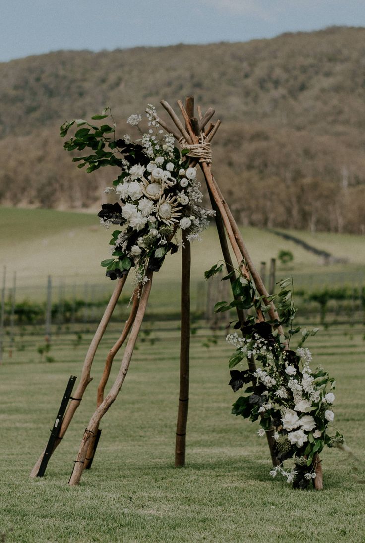 an outdoor ceremony setup with flowers and sticks