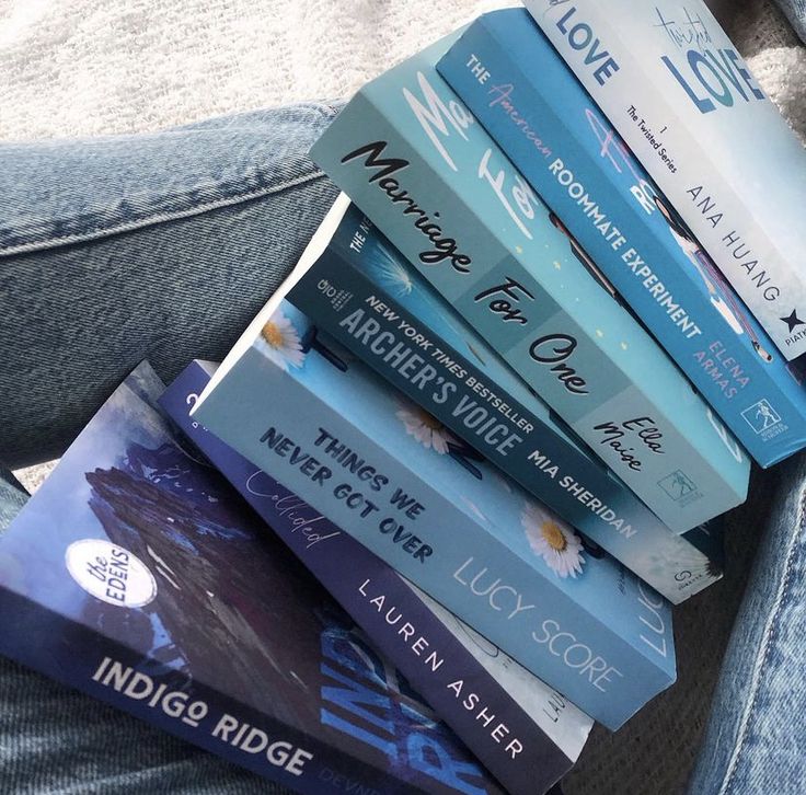 a stack of books sitting on top of a person's lap