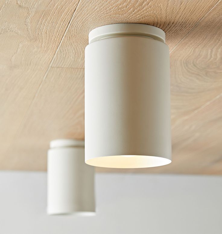 two white lights hanging from the ceiling in a room with wood flooring and walls