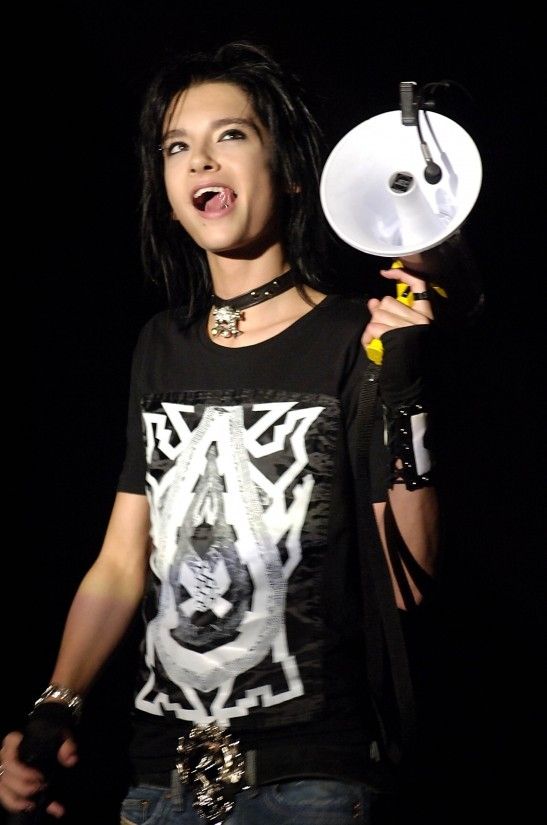 a woman holding a white object in her right hand and wearing a black t - shirt