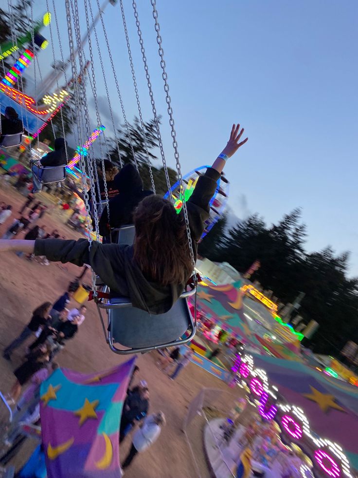 a woman riding on a swing at a carnival