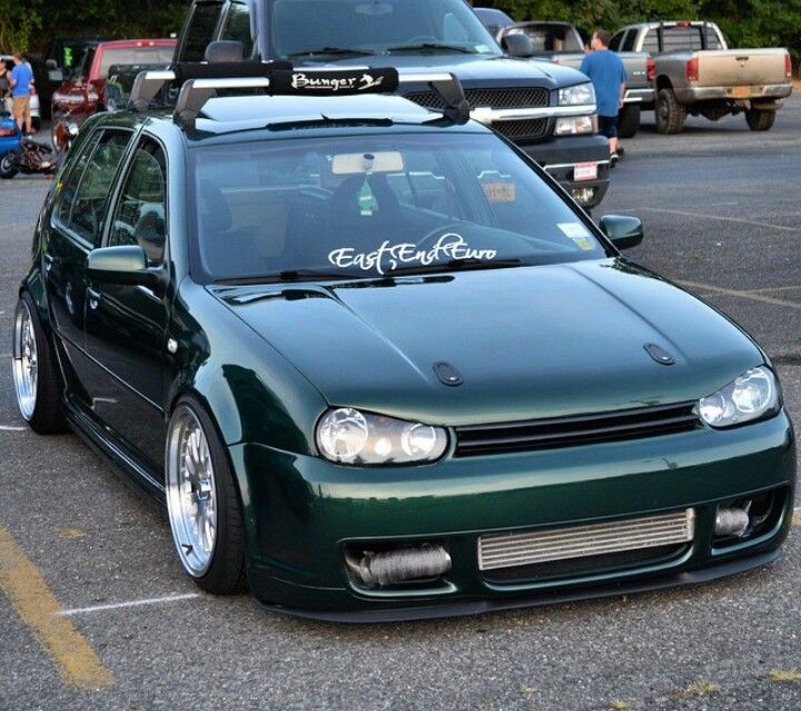 a green car parked in a parking lot next to other cars