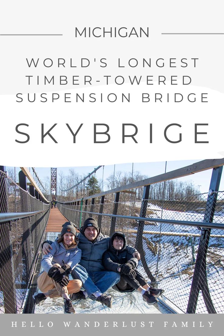 three people posing for a photo on a bridge with the words skybridge above them