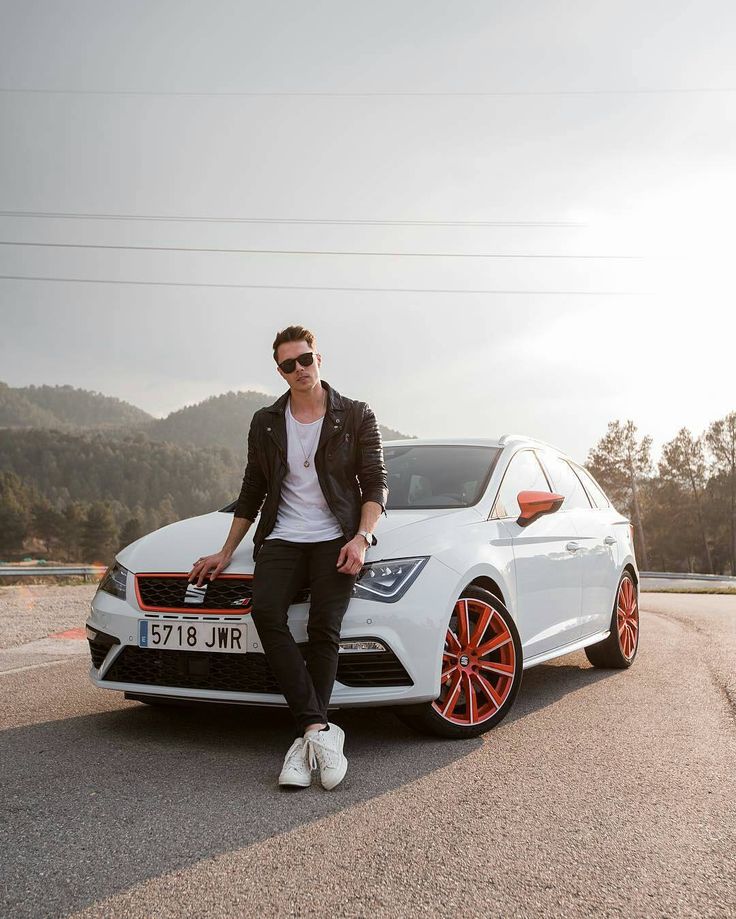 a man sitting on the hood of a white car with red rims and sunglasses