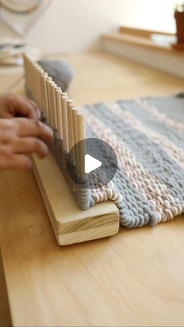 a person is working on an object made out of wooden dows and knitting yarn
