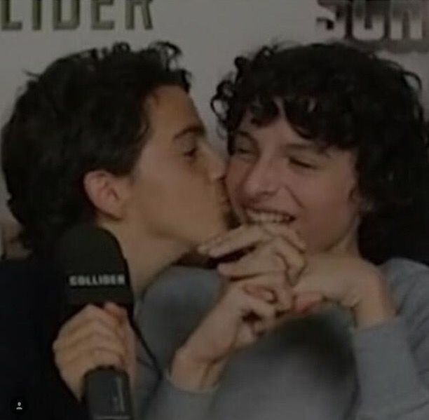 a man and woman kissing each other in front of a microphone