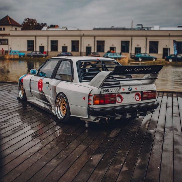 a white car parked on top of a wooden floor next to a body of water