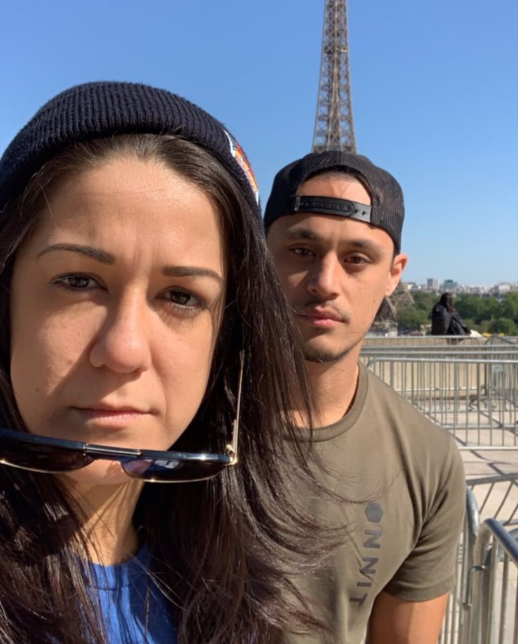a man and woman standing next to each other in front of the eiffel tower