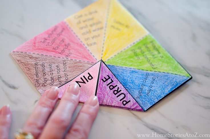 a hand holding a piece of colored paper with writing on it