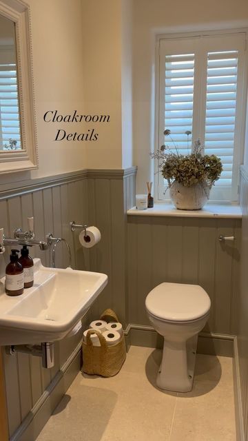 a white toilet sitting next to a sink in a bathroom under a window with shutters