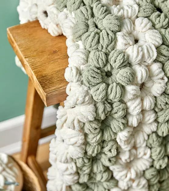 a wooden chair with a green and white blanket on it