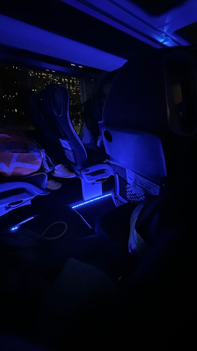 the interior of a car with blue lights and electronics in the passenger seat, along with other items