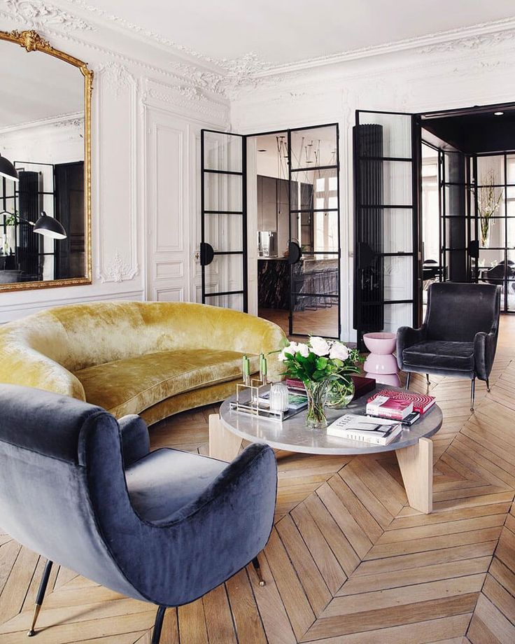 a living room filled with furniture next to a mirror on the wall and wooden flooring