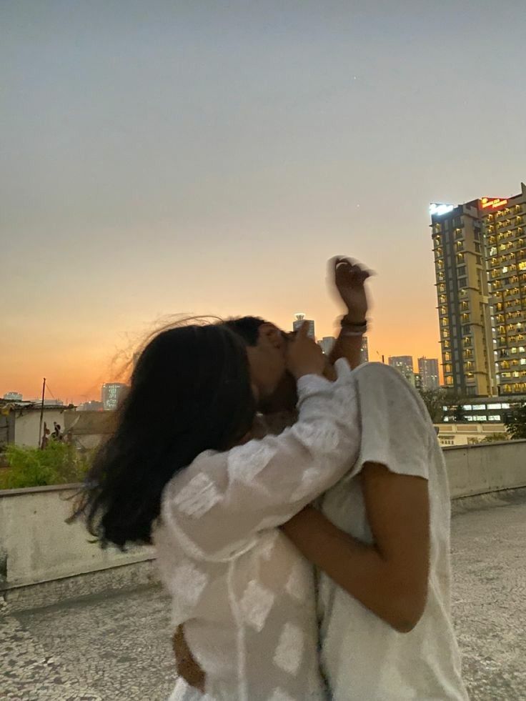 a man and woman kissing in front of a city skyline
