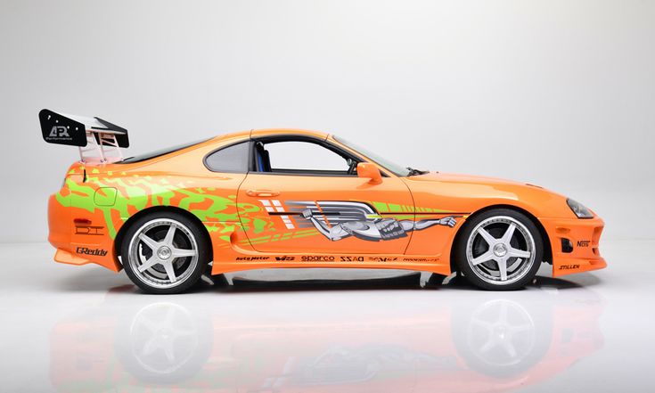 an orange sports car with graffiti on it