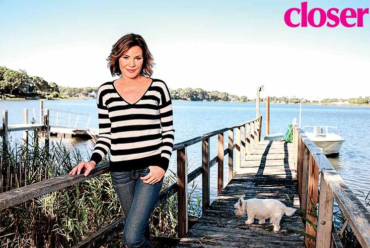 a woman standing on a dock next to a white dog