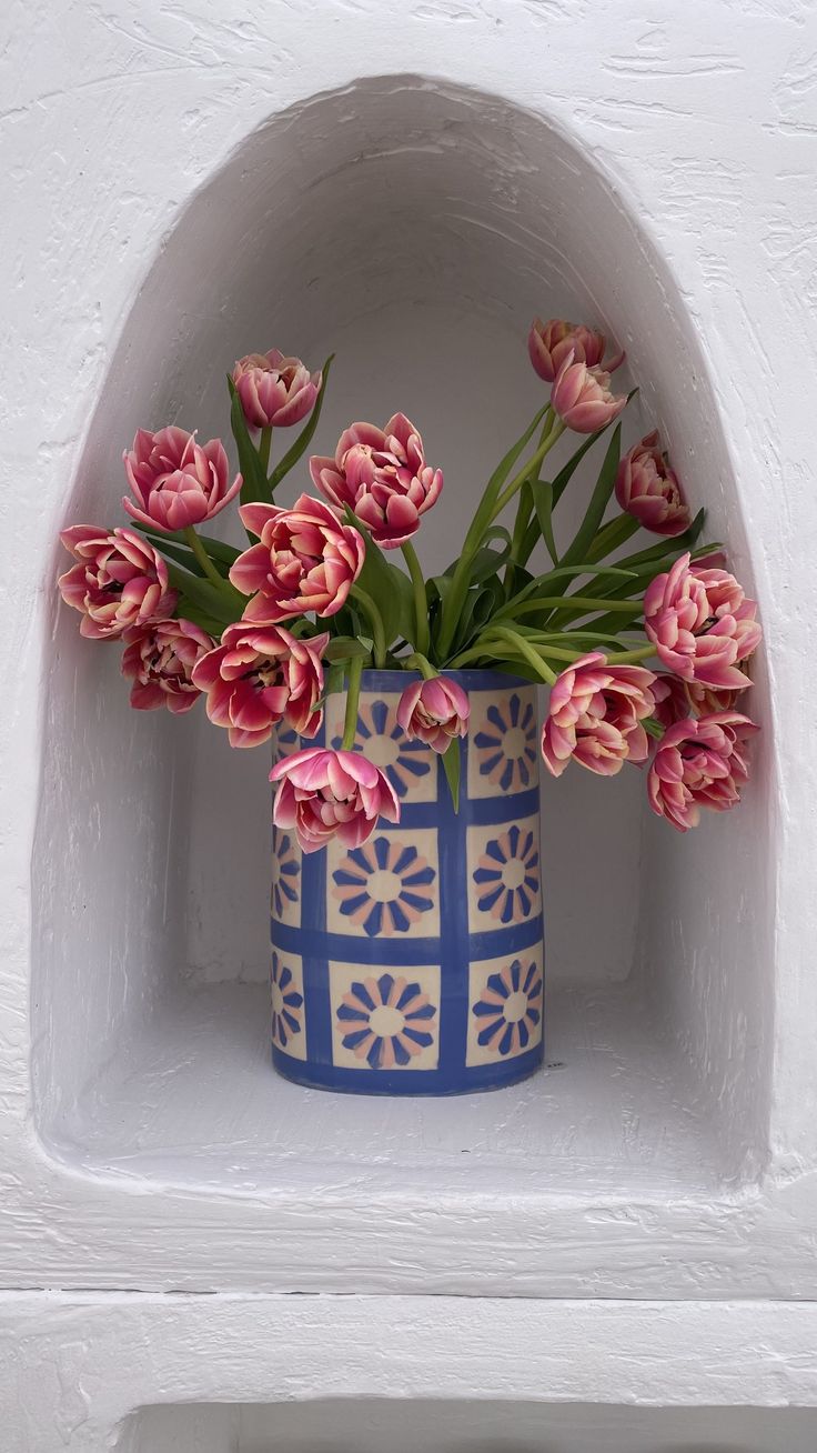 pink tulips are in a blue and white vase