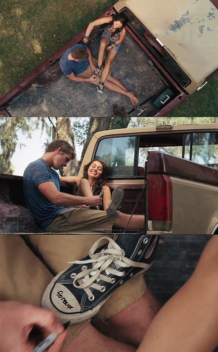 two people sitting in the back of a pick up truck and one person holding a shoe