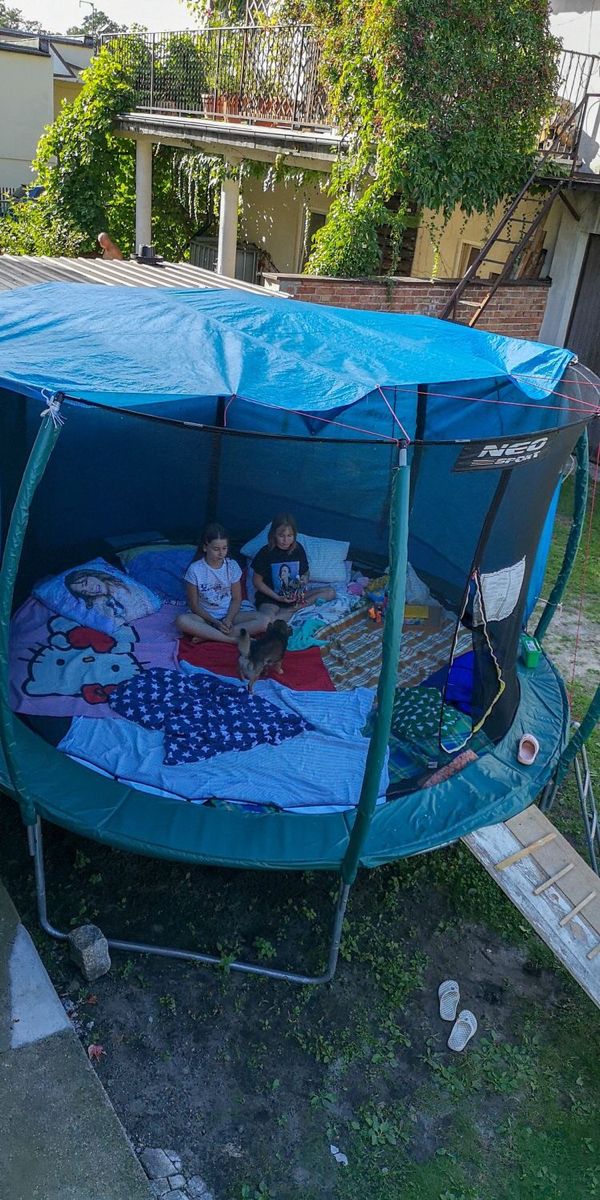 two children are sitting on a bed in a blue tent with the cover over it