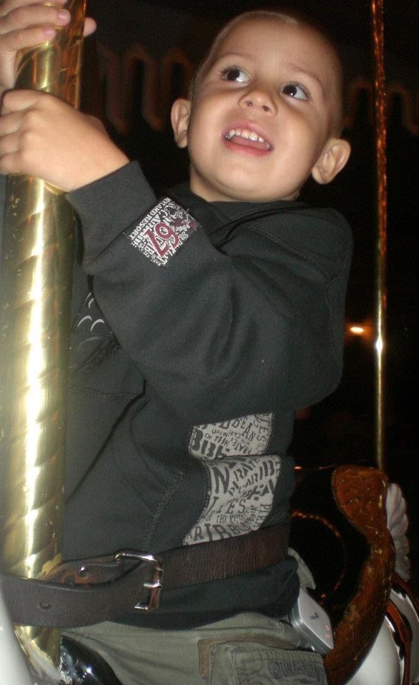 a young boy riding on the back of a white horse with a metal pole in his hand