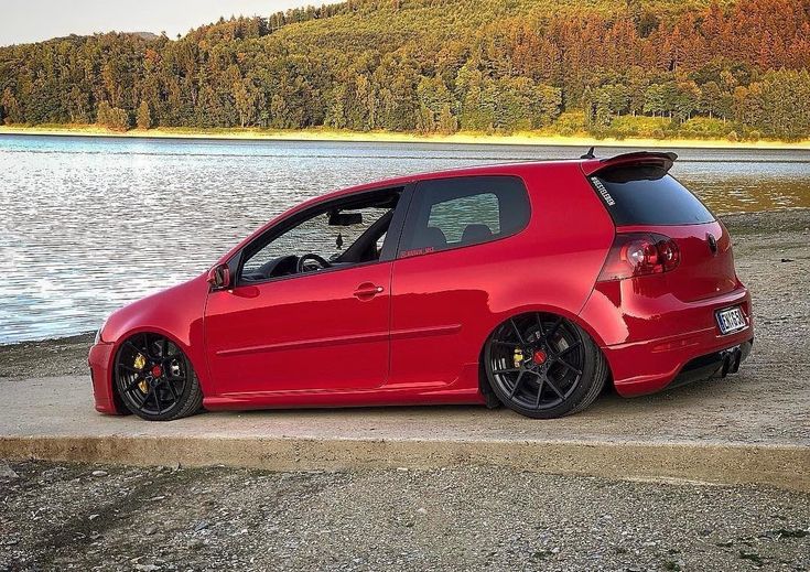 a red car parked next to a body of water