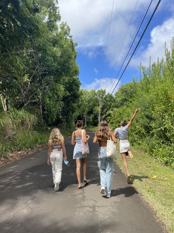 three girls walking down the road with their arms in the air