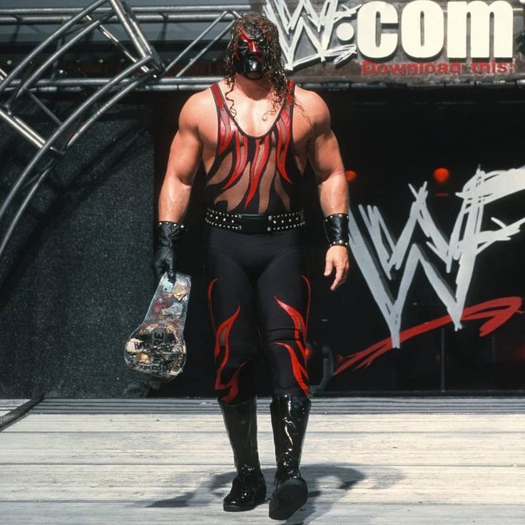 a wrestler walking down the runway with his handbag in his other hand while wearing black and red wrestling gear